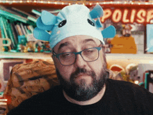 a man with a beard wearing glasses and a blue hat with the word polise behind him