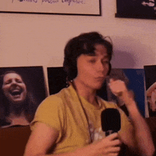 a woman is wearing headphones and holding a microphone in front of a wall with pictures of women on it