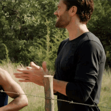 a man standing next to a barbed wire fence clapping