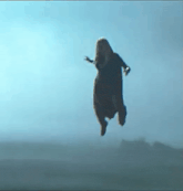 a woman is flying through the air with her arms outstretched in the air .