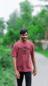 a man wearing a maroon balenciaga t-shirt is walking down a road .