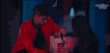 a man and a woman are sitting at a table talking to each other .