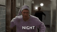 a man wearing a purple sweater and a purple hat is standing in a hallway .