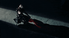 a woman in a black dress is standing in the dark with a red cloth