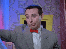 a man wearing a suit and a red bow tie is making a funny face
