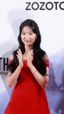 a woman in a red dress is standing in front of a zozoto sign