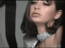 a close up of a woman 's face wearing a choker necklace .