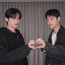 two young men make a heart shape with their hands