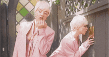 a woman in a pink suit is looking through a door
