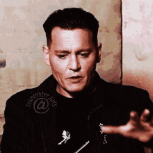 a man wearing a black jacket and a black shirt with the word johnny depp written on it