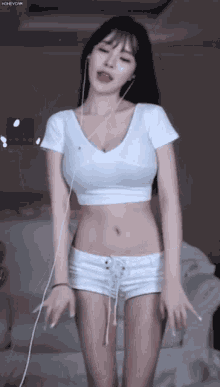 a woman in a white crop top and shorts is dancing in a room .