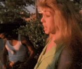 a man and a woman are standing next to each other in a park . the woman is wearing a green dress .