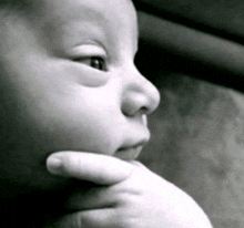 a close up of a baby 's face with a hand on its chin