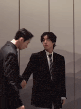 a man in a suit and tie shakes hands with another man in a suit