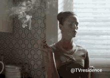 a woman is smoking a cigarette in a kitchen .