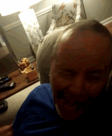 a man in a blue shirt is sitting on a couch with his eyes closed