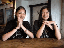 two girls sit at a table with one wearing a t-shirt that says pira