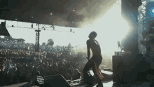 a man dancing on a stage with a crowd behind him and a light behind him that says ' a '