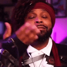 a man with a beard is wearing a red headband and giving a thumbs up .