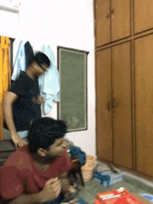a man in a black shirt is standing next to another man in a red shirt in a room