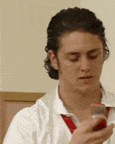 a man in a white shirt and red tie is holding a cell phone in his hand