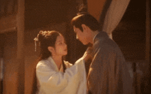 a man and a woman are standing next to each other and touching each other 's faces .