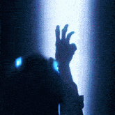 a person 's hand is reaching up towards a blue light