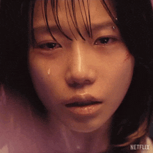 a close up of a girl 's face with a tear coming out of her eye .