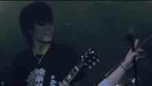 a man playing a guitar and singing into a microphone with the letter d in the corner