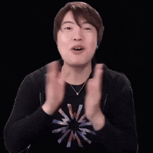 a man wearing a black shirt with a star on it is clapping