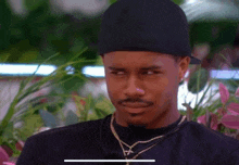 a man wearing a hat and a necklace is looking at something
