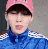 a young man wearing a pink hat and a blue jacket is sticking out his tongue .