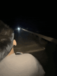 a man is driving down a road at night with a car behind him