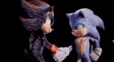shadow the hedgehog and sonic the hedgehog are shaking hands in front of a black background .