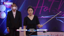 a woman is holding a pool cue in front of a screen that says i news on it