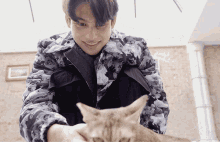a man wearing a louis vuitton jacket holds a cat