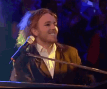 a man is singing into a microphone while playing a piano