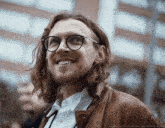 a man with long hair and glasses is smiling and looking up