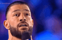 a man with a beard is speaking into a microphone on a stage .