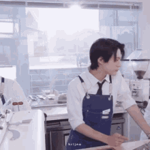 a man in an apron is standing in a kitchen .