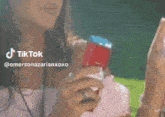 a woman in a pink top is holding a red and blue item