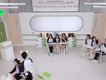 a group of girls are sitting at desks in a classroom with a sign that says ' korean ' on it