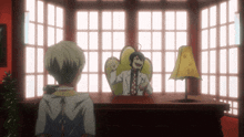 a man in a lab coat sits at a desk with a lamp
