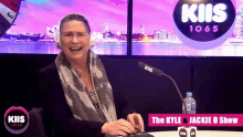 a woman wearing headphones is sitting at a desk in front of a sign that says the kyle & jackie o show