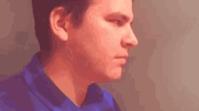 a man in a blue shirt is looking at the camera .