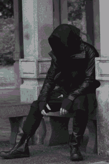 a man in a hooded jacket is sitting on a stone ledge