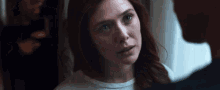 a woman with red hair is looking at a man with a sad look on her face .