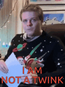 a man in an ugly christmas sweater is holding a piece of paper and says i am not a twink