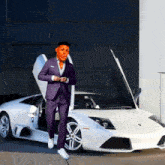a man in a suit is standing in front of a white sports car