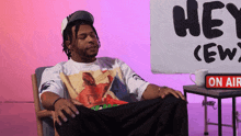 a man sits in front of a sign that says " hey crew "